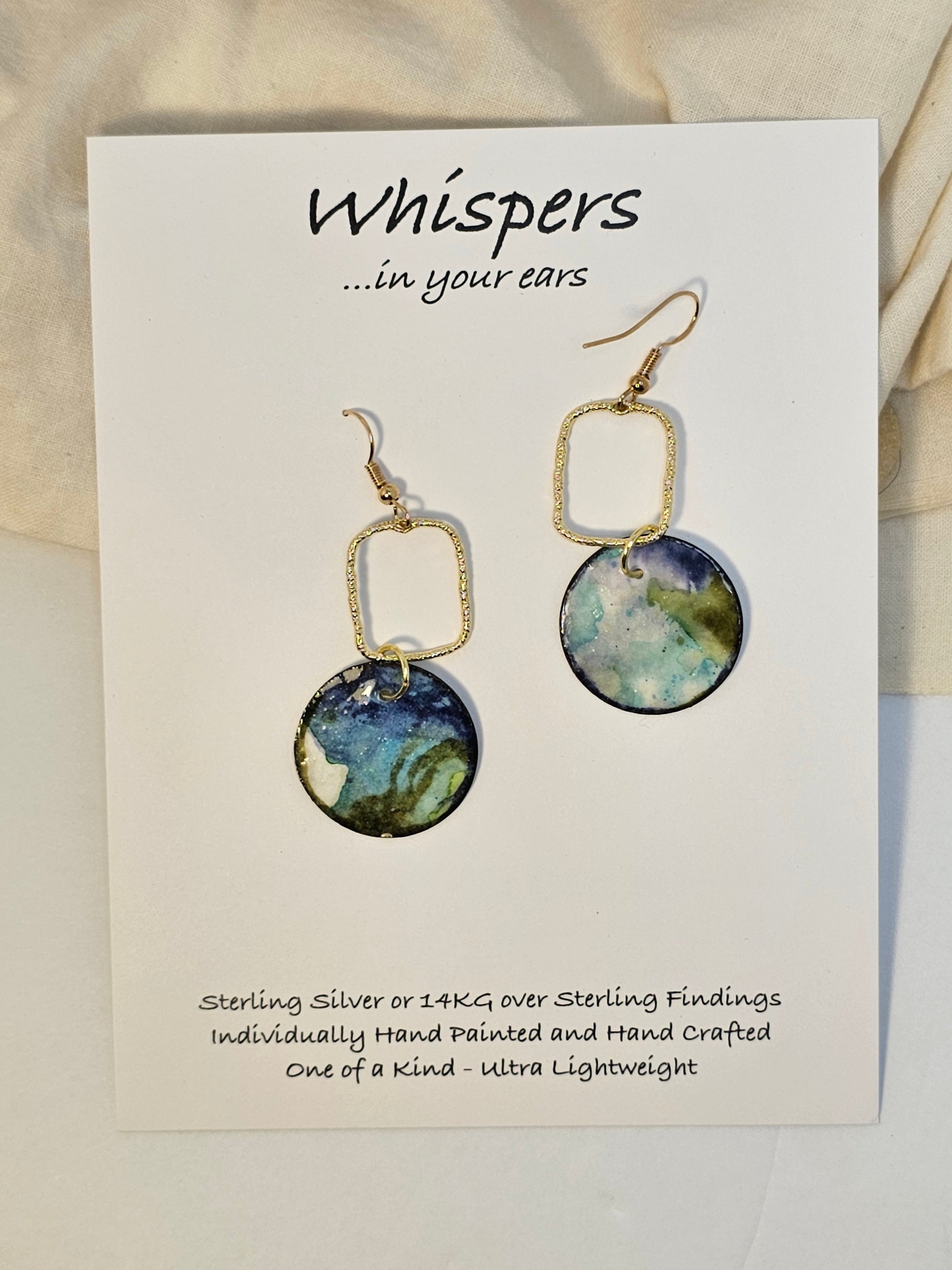 Earth Drop Gold Alloy Rectangle with Hand Painted Paper Earrings. 1" Circular painting in Aqua blue, brown, black and lime green. Hanging from the Gold alloy. Back is painted to match. Ultra lightweight. Resin coating for durability. 14KG over sterling findings. Hangs 1 3/4" in length