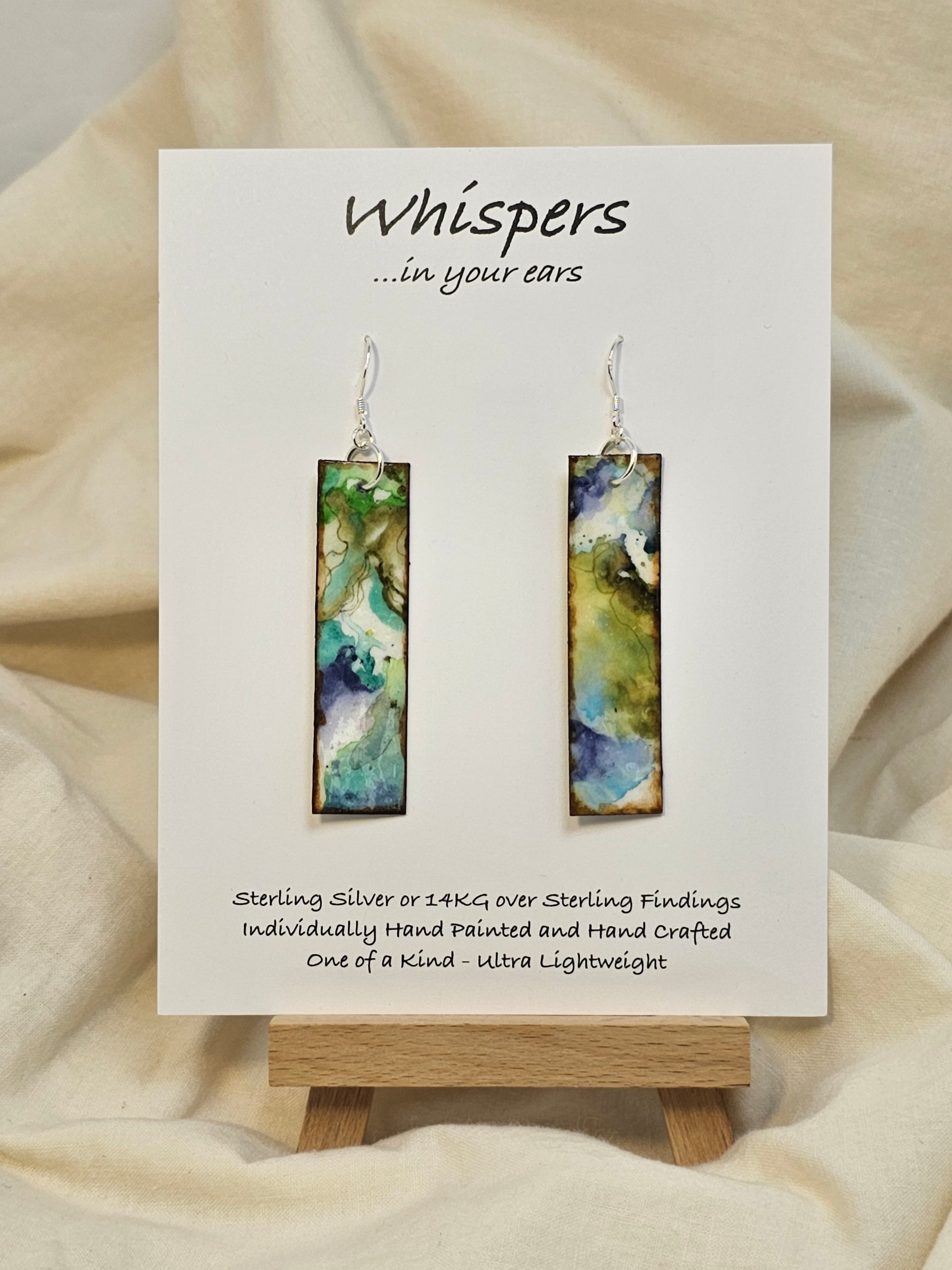 Turquoise Waters Hand Painted Watercolor Paper Earrings. Ultra lightweight, 1/2" x 2 1/4" Rectangle painted in watercolor abstract aerial view of turquoise blue waters and green land. Back is complimentary colors and design. Edged in brown paint. Resin coating for durability. Sterling silver findings. Hangs 2 1/2" in length
