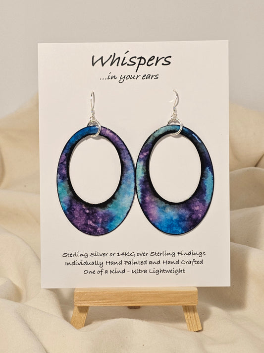 Galaxy Statement Hand Painted Paper Earrings. 2 1/2" Oval with cut out.&nbsp; Statement. Watercolor painted turquoise blue, aqua and purple. Back is painted to match. Edged in black. Resin coating for durability. Sterling Silver findings. Hangs 2 3/4" in length