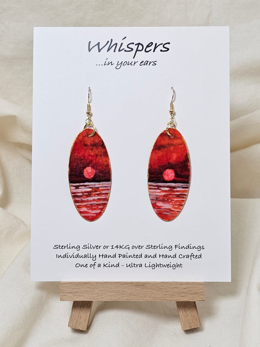 Red Sky Morning Hand Painted Paper Earrings. Ultra lightweight elongated 2" oval. Watercolor red, orange, white and gold sunrise over water. Back painted in similar color. Resin coating for durability. 14KG over sterling findings. Hangs 2 1/4" in length