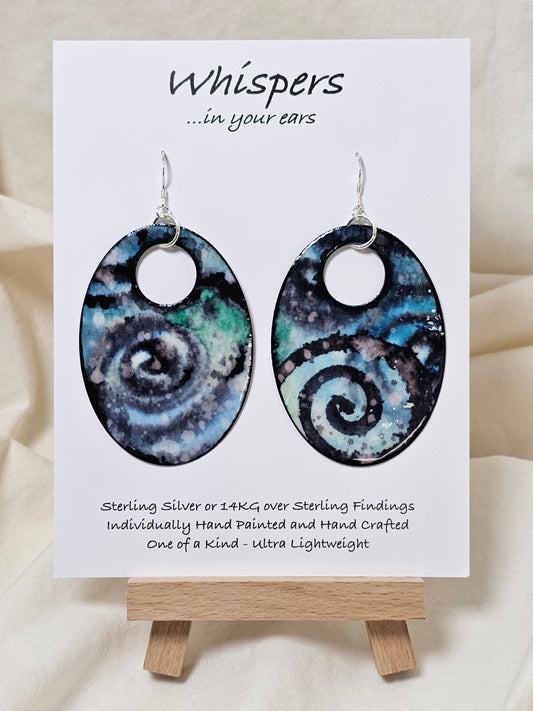 Cosmic Energy Hand Painted Paper Earrings.&nbsp; Ultra lightweight 2 1/2" Statement Oval with small circular cut out. Watercolor blues, greens and black. Abstract design. Back is painted in similar colors. Resin coating for durability. Sterling Silver findings. Hangs 2 3/4" in length