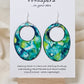 Caribbean Waters Hand Painted Paper Earrings. Ultra lightweight 2 1/2" Statement Oval with medium circular cut out. Watercolor blues, greens and turquoise. Abstract design. Back is painted in similar colors. Resin coating for durability. Sterling Silver findings. Hangs 2 3/4" in length