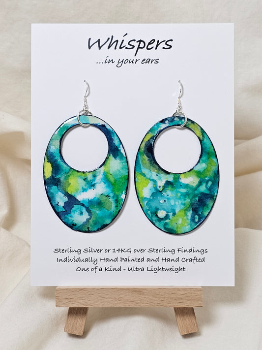 Caribbean Waters Hand Painted Paper Earrings. Ultra lightweight 2 1/2" Statement Oval with medium circular cut out. Watercolor blues, greens and turquoise. Abstract design. Back is painted in similar colors. Resin coating for durability. Sterling Silver findings. Hangs 2 3/4" in length