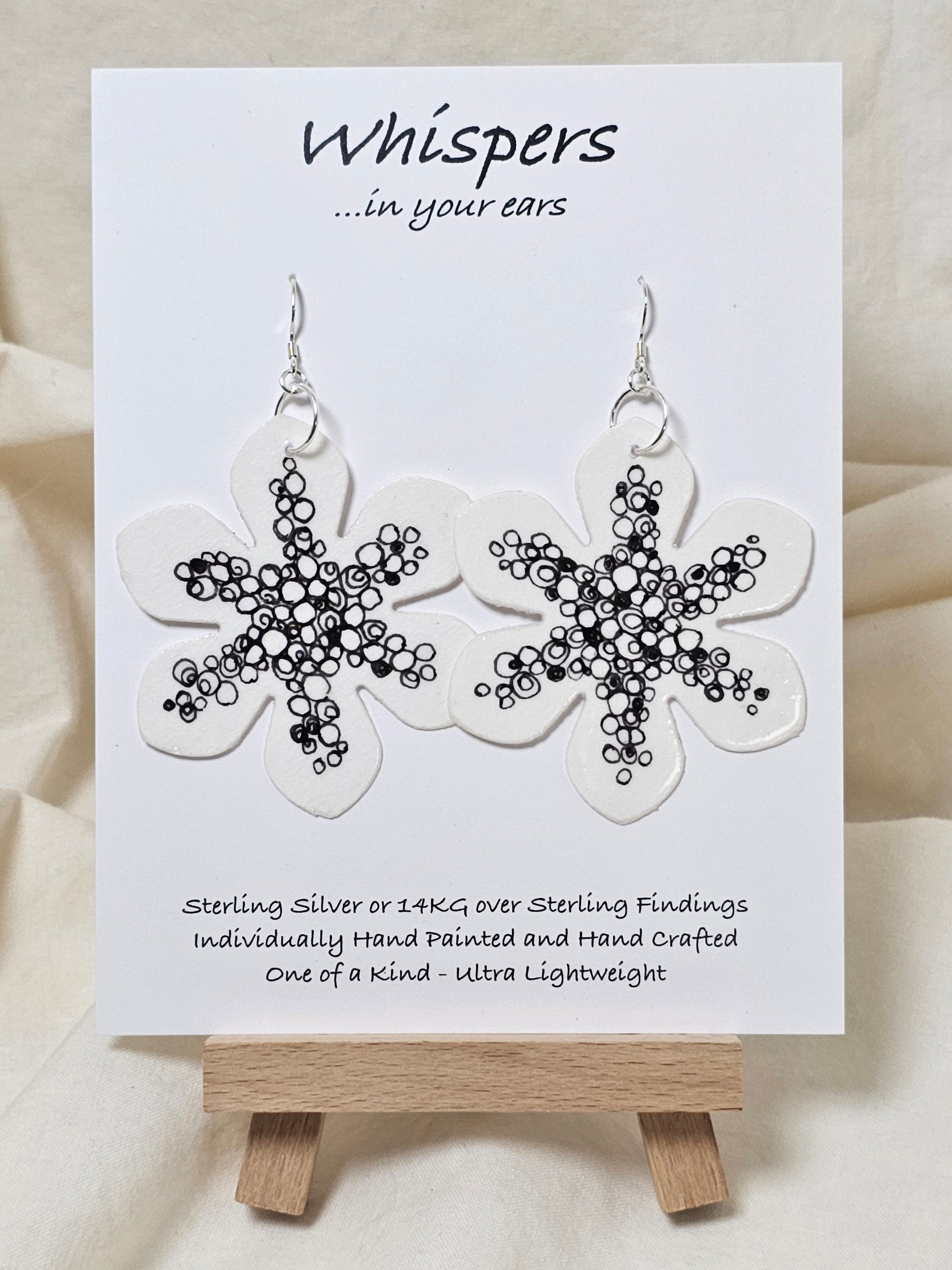 Interconnection in Black and White Flower Hand Painted Paper Earrings. Ultra lightweight 2 1/2" in diameter. Watercolor painted to resemble bright white flower with numerous interconnecting circles and swirls. Back is painted with same design. Resin coating for durability. Sterling Silver findings. Hangs 2 5/8" in length