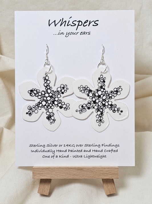 Interconnection in Black and White Flower Hand Painted Paper Earrings. Ultra lightweight 2 1/2" in diameter. Watercolor painted to resemble bright white flower with numerous interconnecting circles and swirls. Back is painted with same design. Resin coating for durability. Sterling Silver findings. Hangs 2 5/8" in length