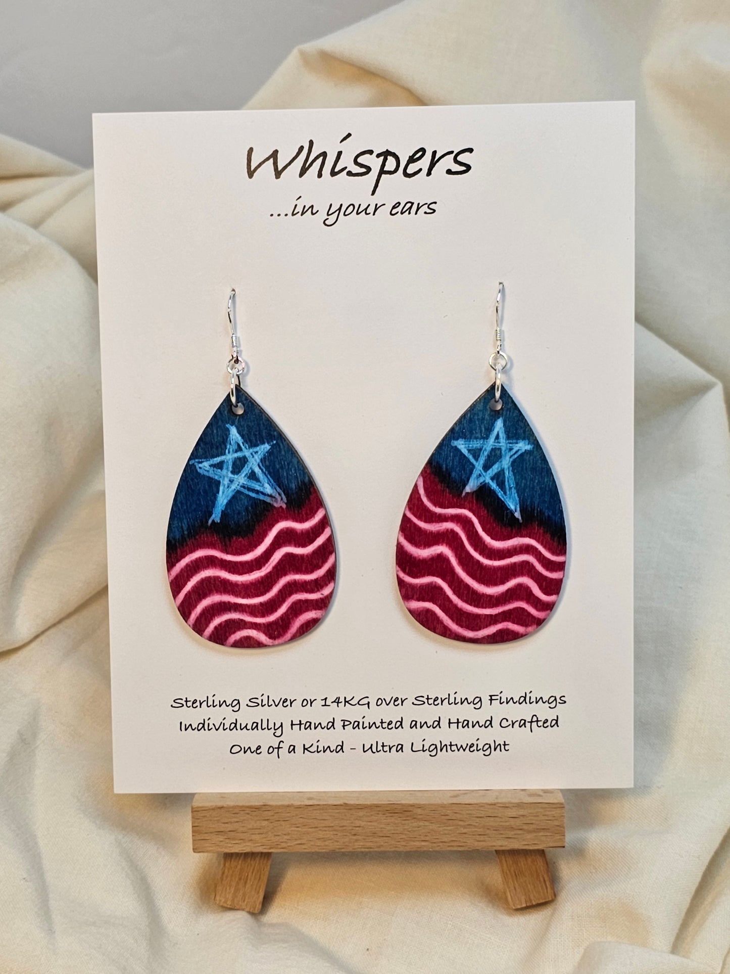 Americana Wood Earrings. 2" Tear drop. Painted in watercolor and acrylic stars and stripes. Red, white and blue. Back is painted to match. Enameled for durability. Sterling silver findings. Hangs 2 1/4" in length