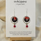 Red Skies Hand Painted Paper and Silver Alloy Earrings. 3/4" Circular watercolor painting of trees and mountains in silhouette against a red sky. Painting hanging in the center of a silver alloy circle. below hangs a red bead embellishment. Back is painted to match. Sterling Silver findings. Resin coating for durability. Hangs 2 1/8" in length