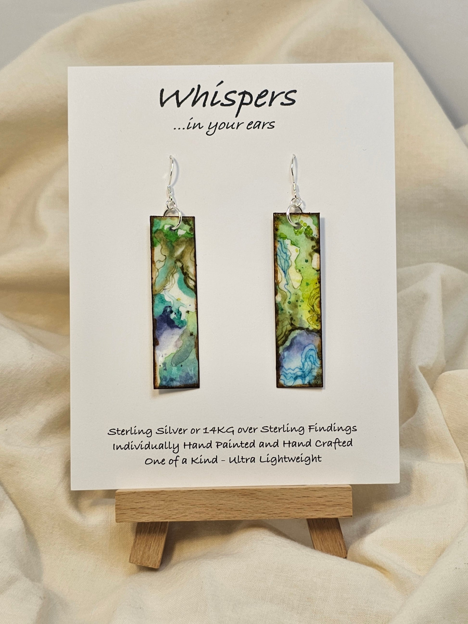 Turquoise Waters Hand Painted Watercolor Paper Earrings. Ultra lightweight, 1/2" x 2 1/4" Rectangle painted in watercolor abstract aerial view of turquoise blue waters and green land. Back is complimentary colors and design. Edged in brown paint. Resin coating for durability. Sterling silver findings. Hangs 2 1/2" in length