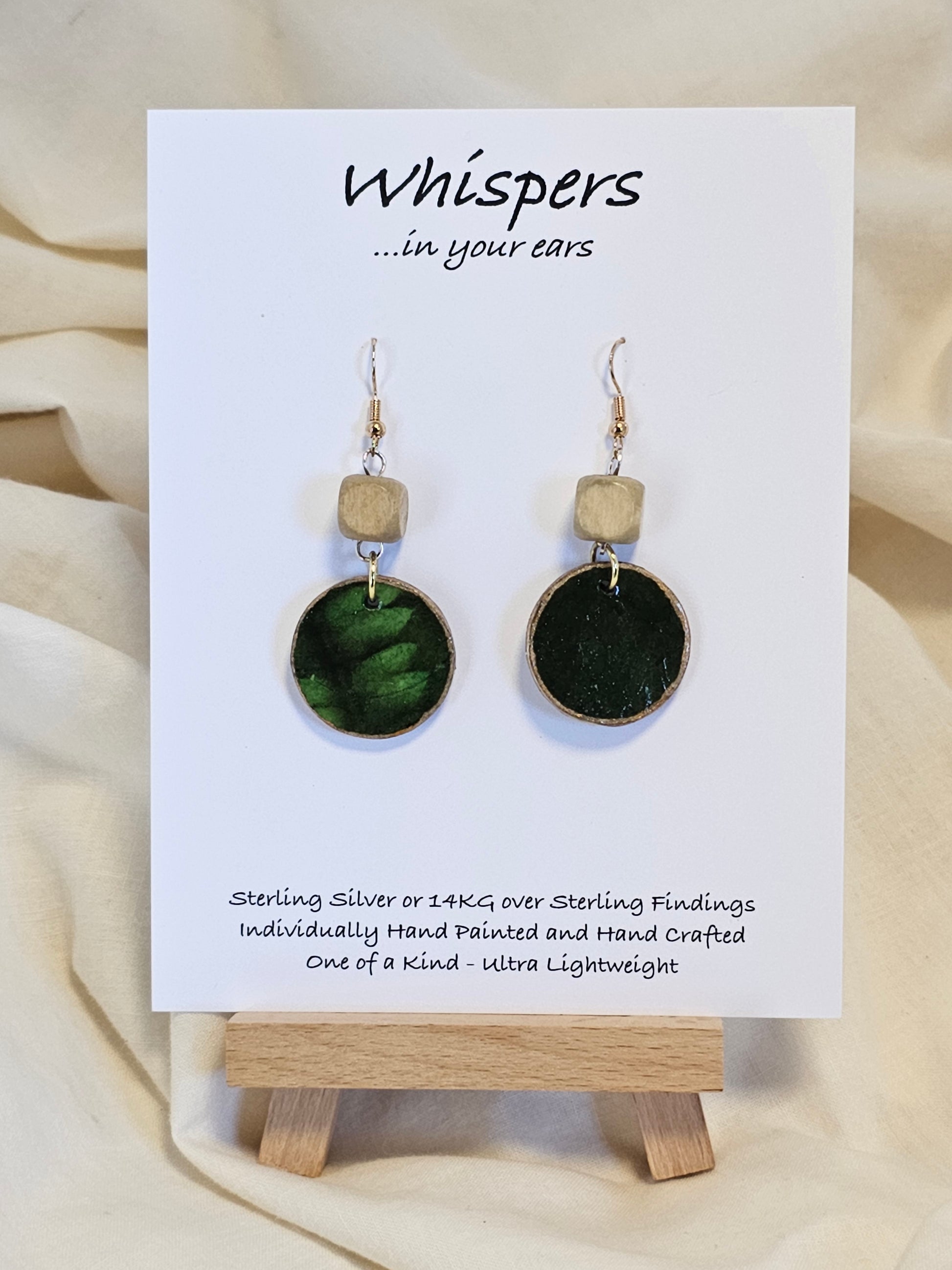 Leaf Relief Hand Crafted Wood Earrings. 1" Wood Disc with two tone green handmade paper painted gold edges and hanging from cream colored square wooden bead. Resin Coating for durability. Back is done to compliment. 14kg over sterling ear wire sterling silver findings. Hangs 1 3/4"