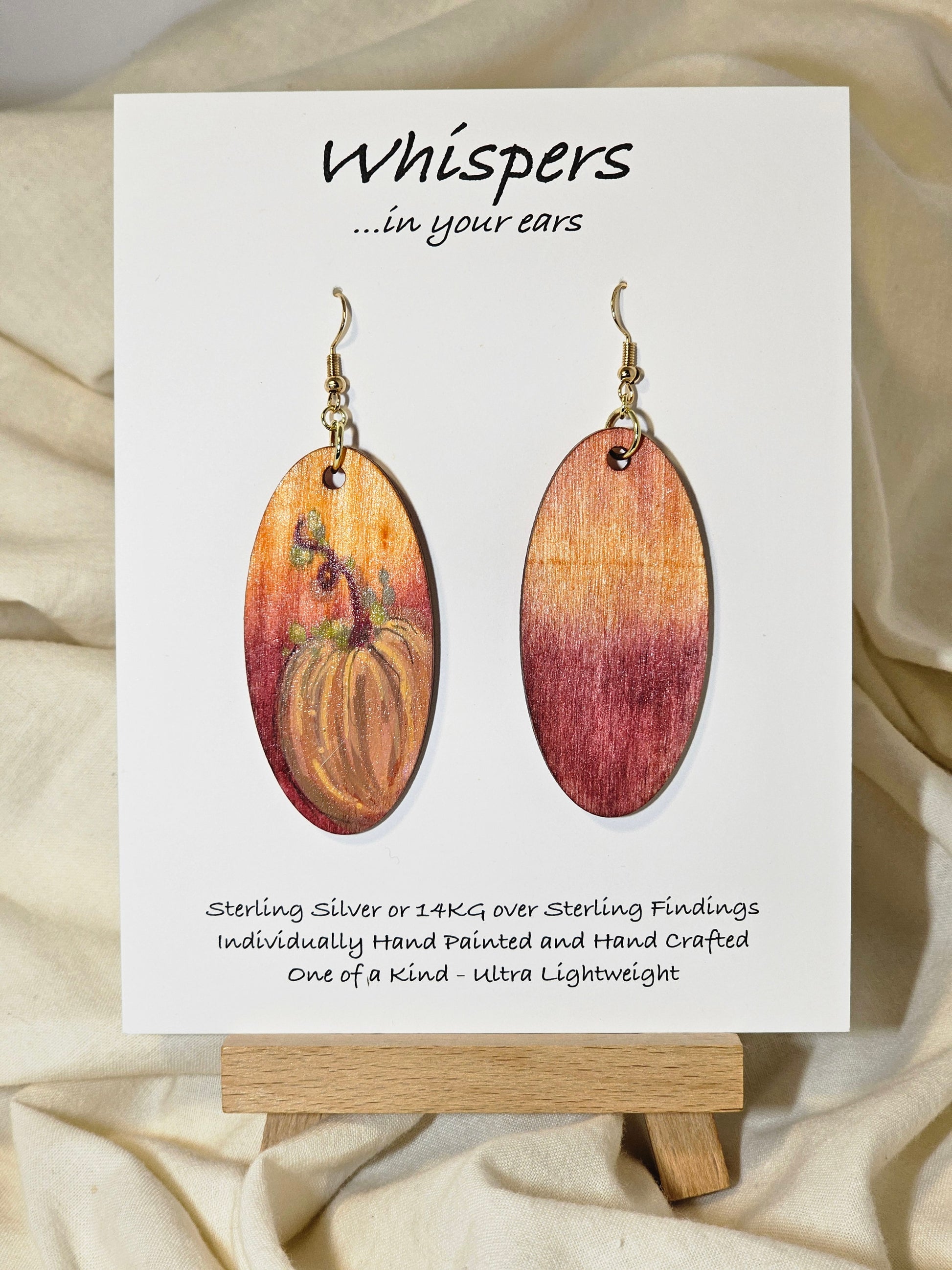 Pumpkin Glow Hand Painted Wood Earrings. Ombre background orange and red. Back painted in similar colors. Enameled for durability. 2" Elongated wood oval. 14kg over sterling silver findings and hangs 2 1/4"