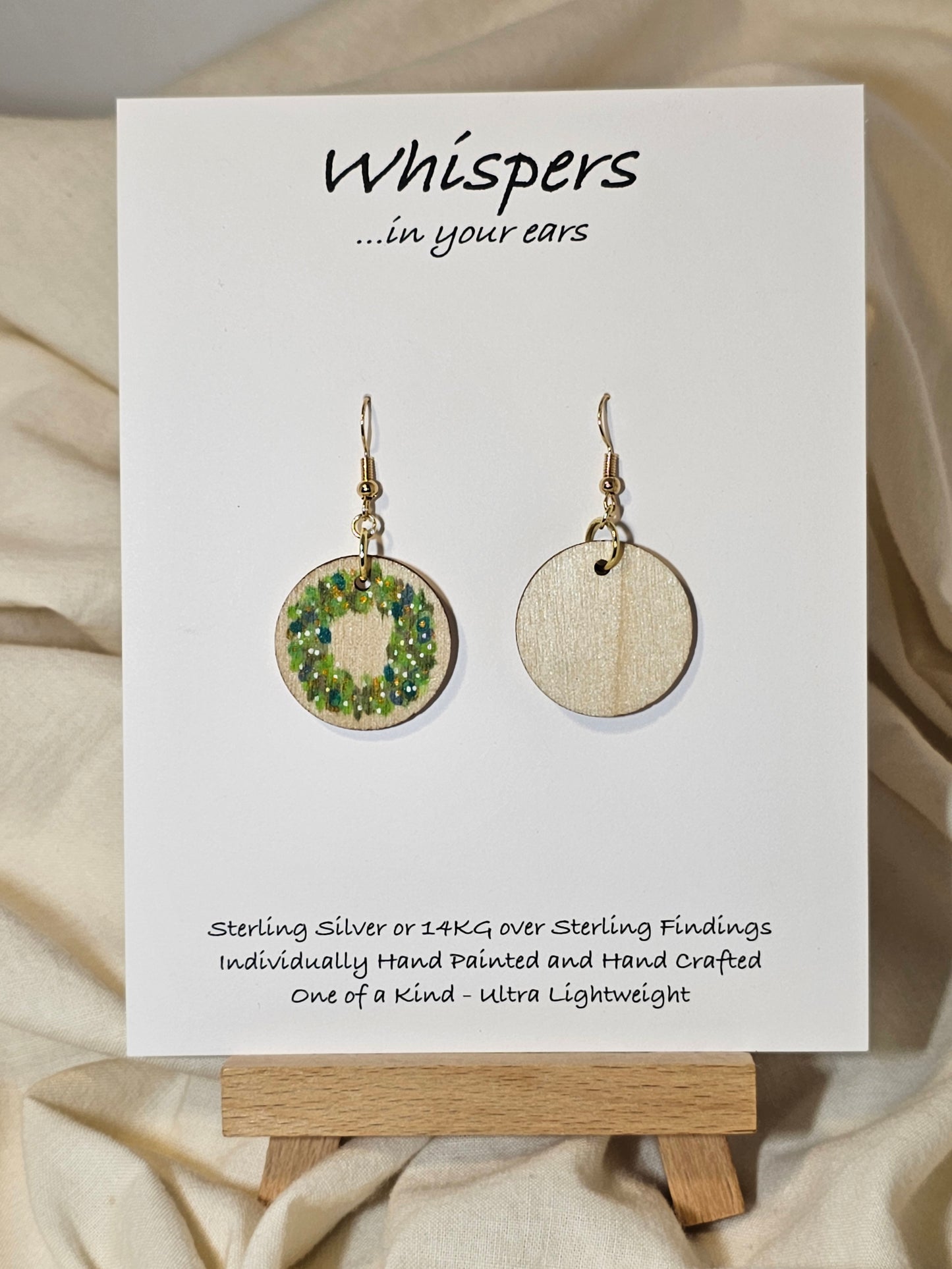 Holiday Wreath Hand Painted Wood Earrings. 1" Stained wood round, two toned Holiday wreath painted with white and colored berries. Ultra light weight. Back of earring is stained natural. Enameled for durability. 14kg over sterling ear wires and findings. Hangs 1 1/4"