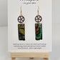 Copper Steampunk Hand Painted Paper and Wood Earrings. 1/2" x 1 5/8" Paper Rectangle hand painted brightly colored background with silver and copper accents. Edged in black. Hanging from Copper notched circular gear. Back is painted to match. Resin coating for durability. Sterling Silver findings. Hangs 2 1/2" in length