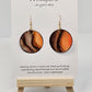 Wooden Glow Hand painted Paper earrings. Look of wood in bark pattern, orange glow and brown and dark brown lines. Gold metallic veining. Back of earring is painted to match. Ultra lightweight. Resin coated for durability. 1 1/2 "diameter. 14KG over Sterling findings. Hangs 1 3/4" in length