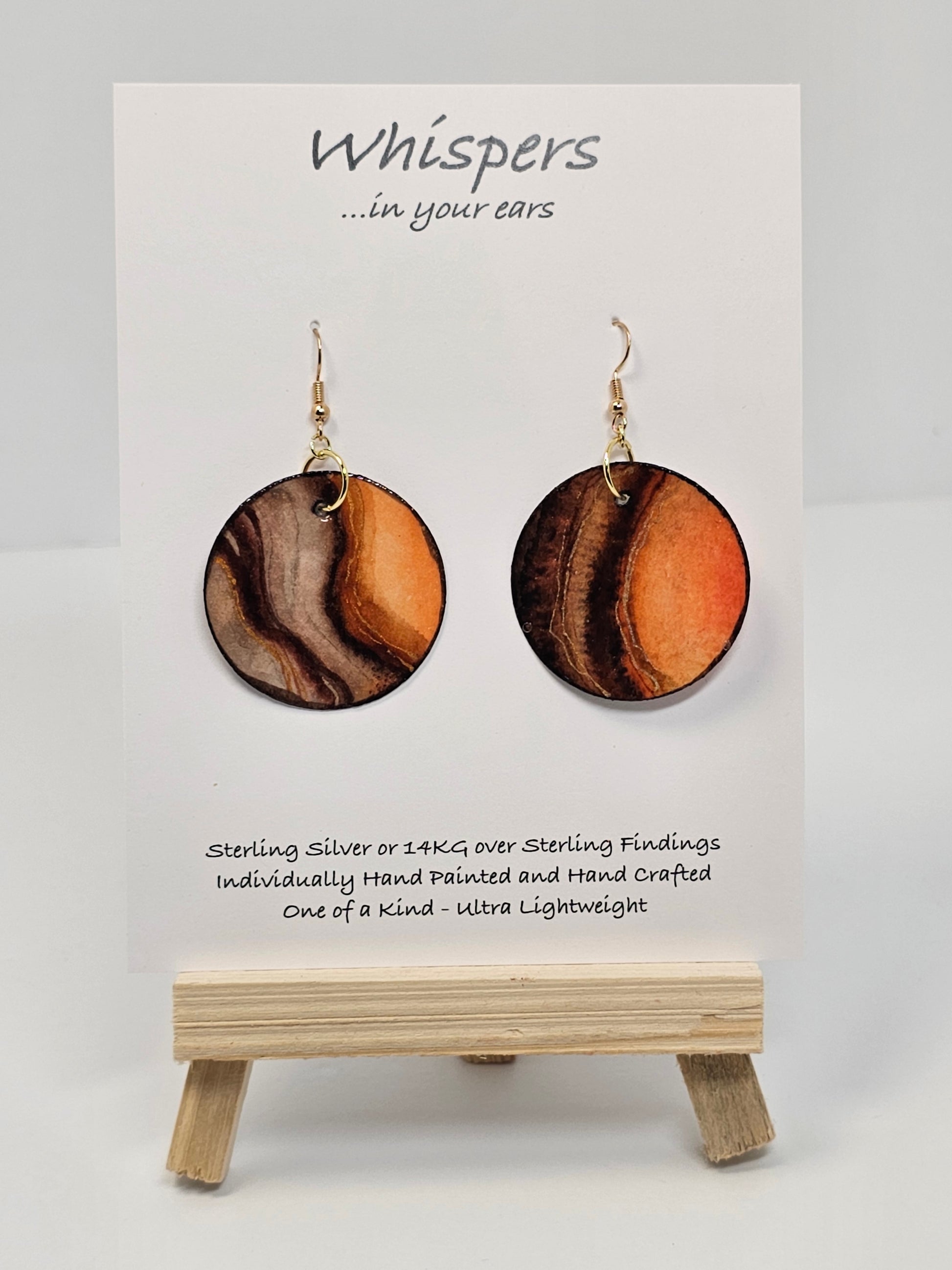 Wooden Glow Hand painted Paper earrings. Look of wood in bark pattern, orange glow and brown and dark brown lines. Gold metallic veining. Back of earring is painted to match. Ultra lightweight. Resin coated for durability. 1 1/2 "diameter. 14KG over Sterling findings. Hangs 1 3/4" in length