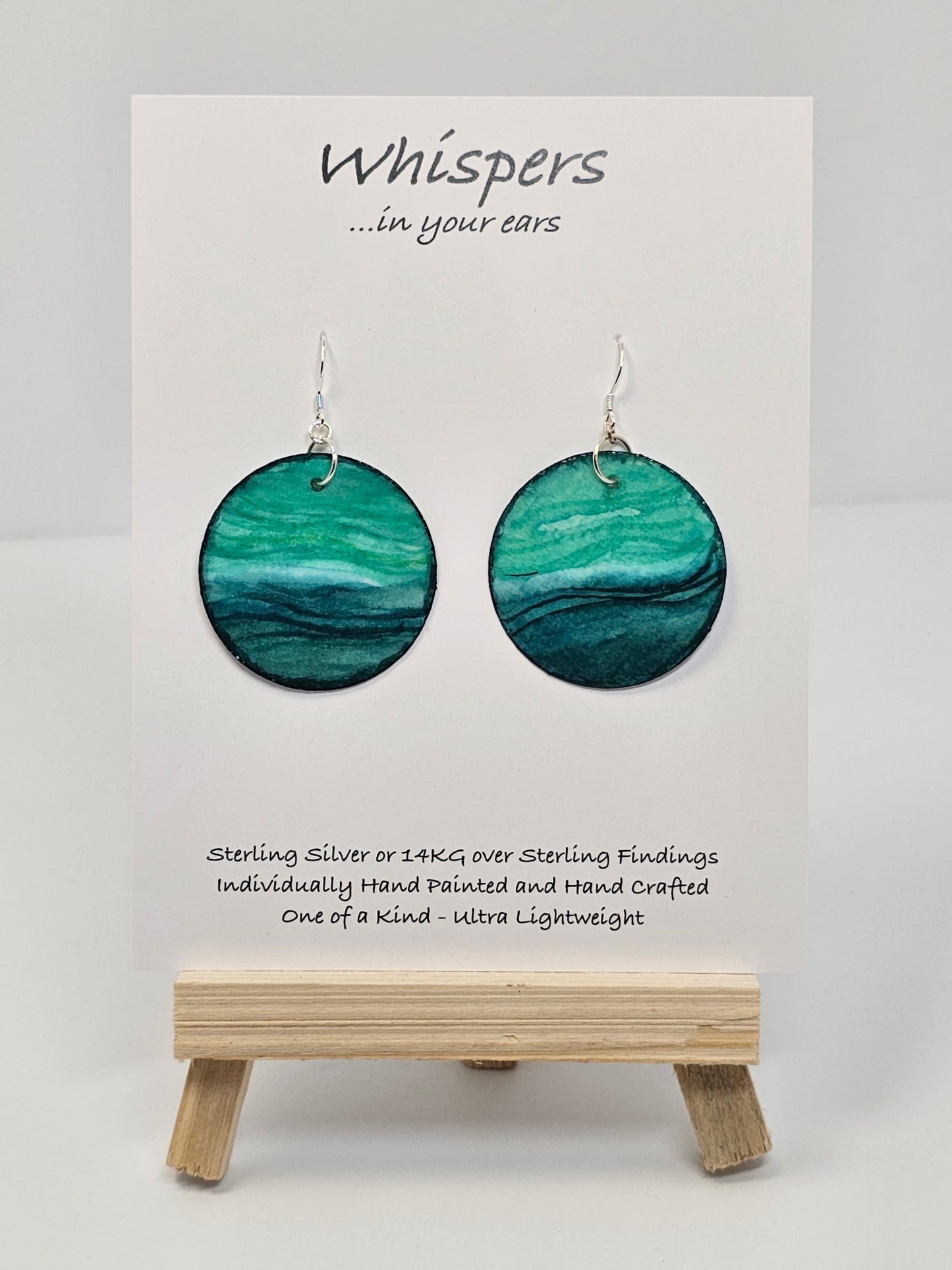 Aqua Blue and teal hand painted paper earrings. Done in watercolor. Impressionistic ocean scape. Circular in shape. Back of earring is painted to match. Ultra lightweight. Resin coated for durability. 1 1/2 in diameter. Sterling findings. Hangs 1 3/4" in length