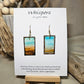 Metallic Beach Hand Painted Paper Earrings. Ultra lightweight 3/4" x 1 1/2" rectangle painted with watercolor. Depicts impressionistic beachscape. Metallic accents in sand. Edges painted in dark brown to frame the scene. Back is painted with the same design. Resin coating for durability. 14kg over sterling silver ear wires. Mixed metals. Hangs 1 3/4" in length