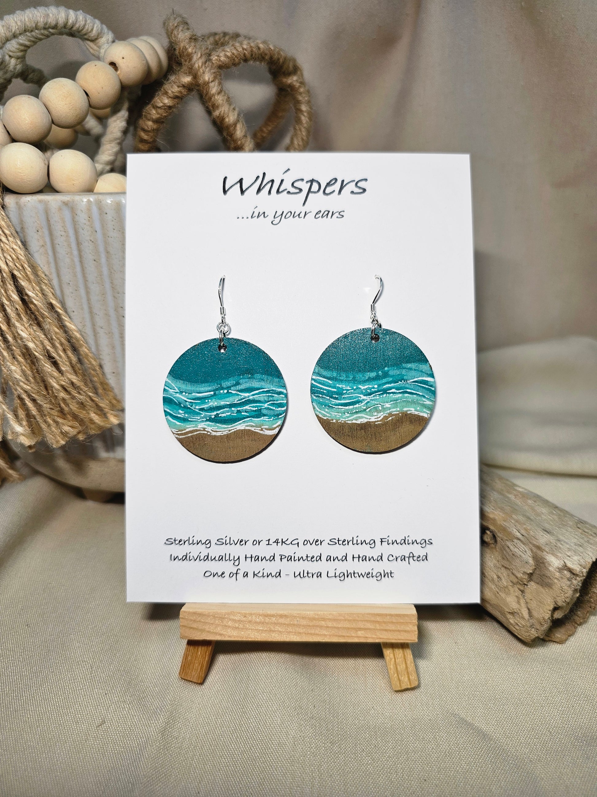 Shore Break Hand Painted Wood Earrings. 1 1/2" wooden round, Beach shoreline landscape painted with acrylics in aqua blues, teal and white. Ultra light weight. Back of earring is painted with similar design. Enameled for durability. Sterling silver ear wires and findings. Hangs 1 3/4"