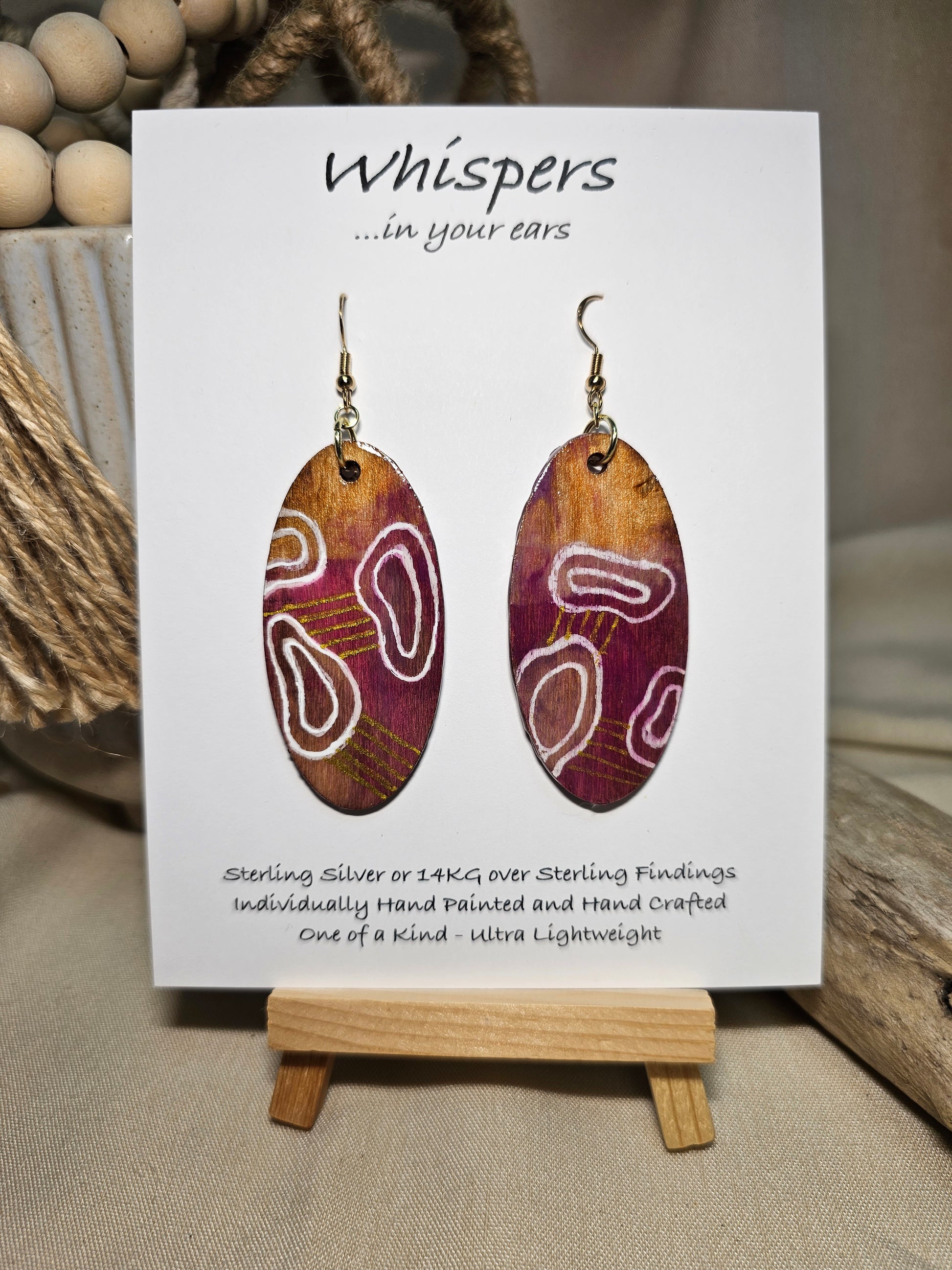 Organic Boho Hand Painted Wood Earrings. Organic shapes and metallic lines painted in acrylics. Back is painted in similar color. Ultra light weight. Resin coating for durability. 2" Elongated wood oval. 14kg over Sterling silver mixed metals with sterling silver findings and hangs 2 1/4" in length