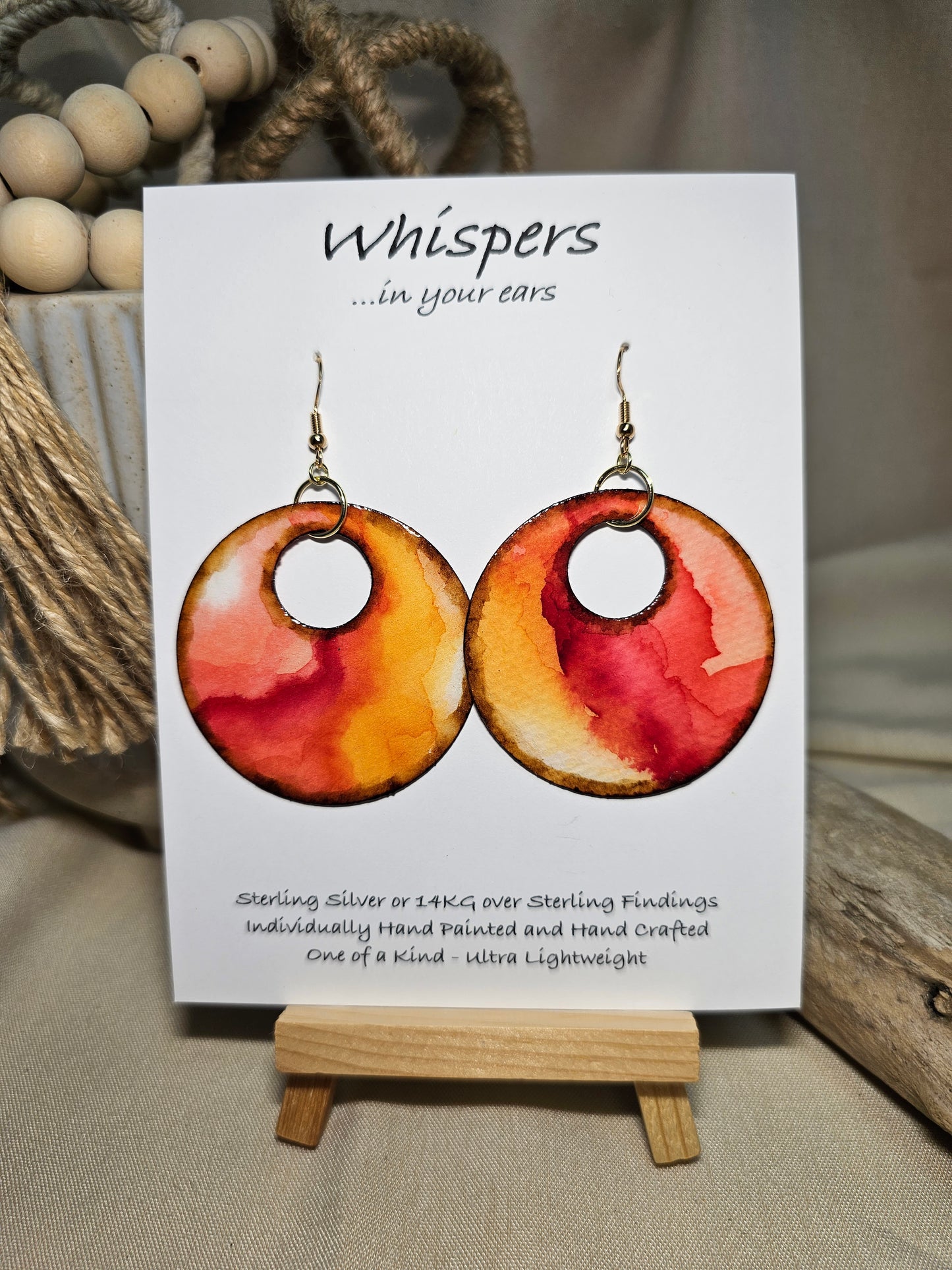 Crimson Tide Hand painted watercolor ultra lightweight paper earrings. 2" circle Waves of red, peach , pink and brown on white background. Dark brown detail painted edge. Back is painted with similar color and design. Large circular in shape with circular cut out. Resin coating for durability. 14kg over Sterling silver findings. Hangs 2 1/4" in length