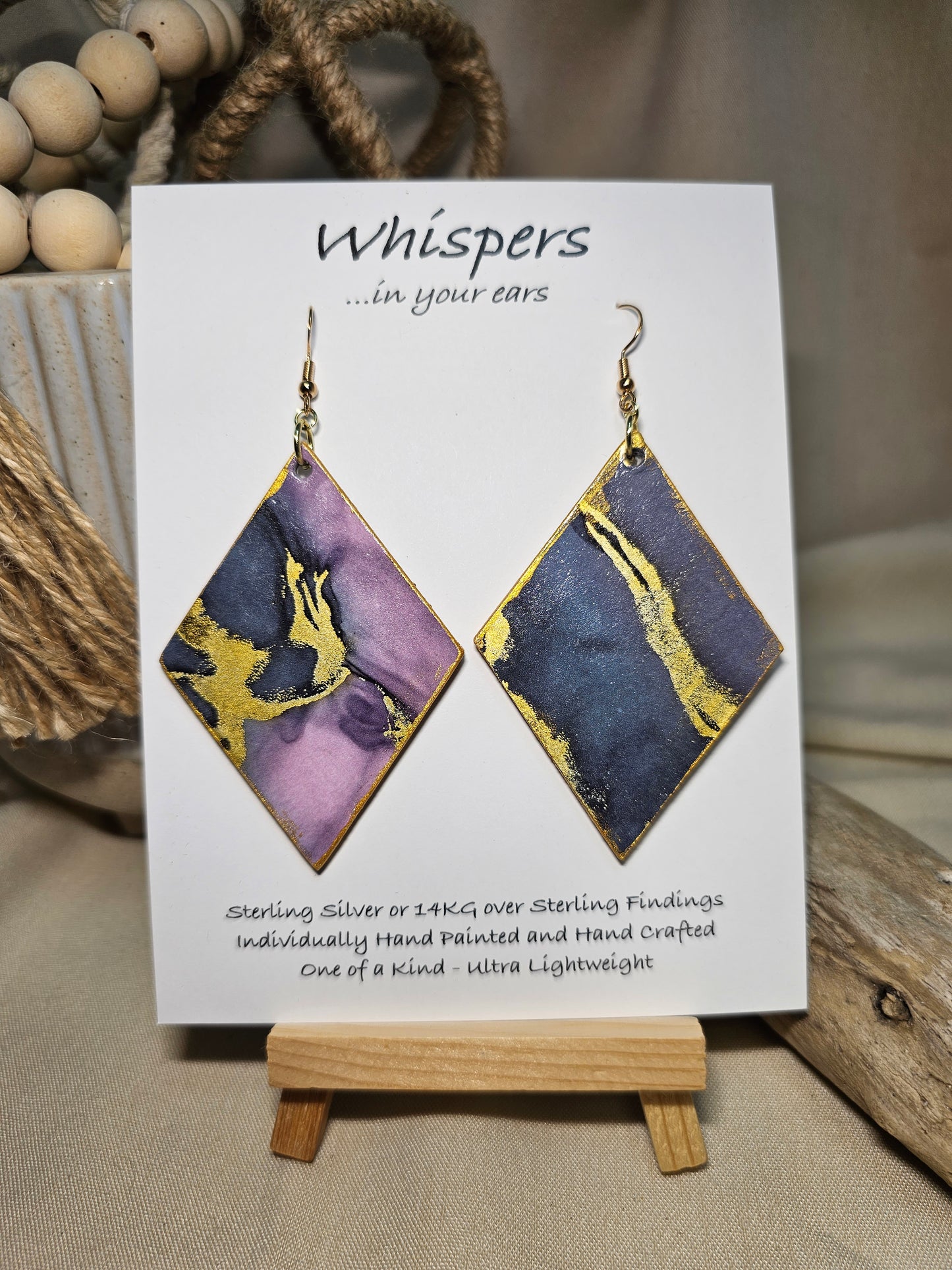 Diamond Flow Large Statement Hand Painted and collage embellished Diamond Shape Wood Earrings. Organic shapes and metallic lines,. Blues, purples and gold. Painted gold metallic edges. Back is in similar color and design. Ultra light weight. Enameled for durability. 2 3/4" in size. 14kg over sterling silver findings and hangs 3" in length