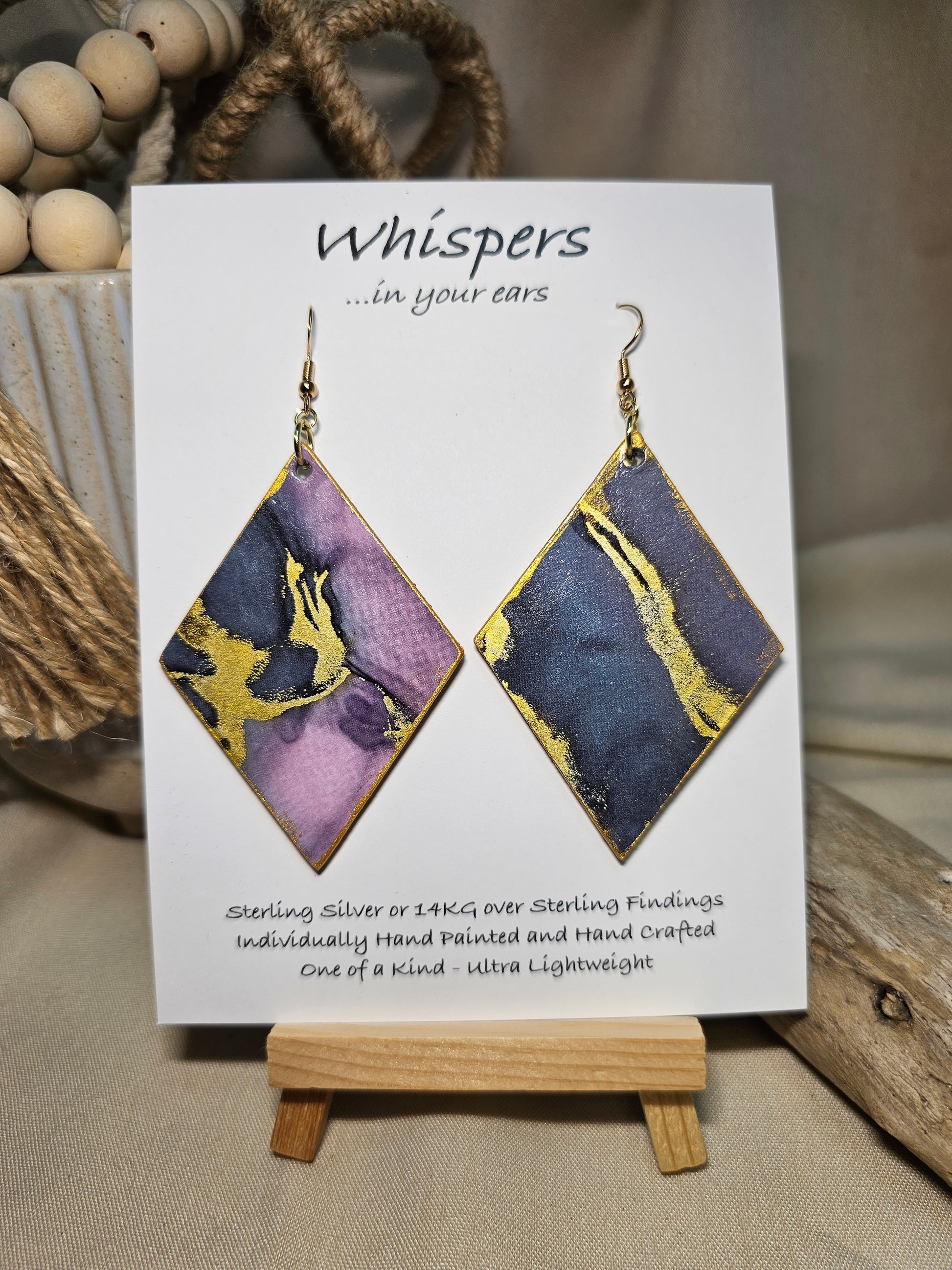 Diamond Flow Large Statement Hand Painted and collage embellished Diamond Shape Wood Earrings. Organic shapes and metallic lines,. Blues, purples and gold. Painted gold metallic edges. Back is in similar color and design. Ultra light weight. Enameled for durability. 2 3/4" in size. 14kg over sterling silver findings and hangs 3" in length