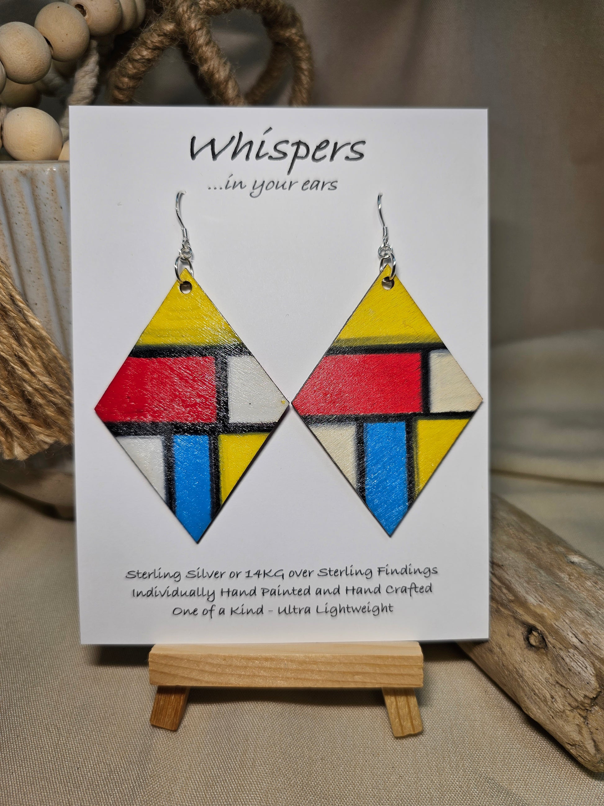 Mondrian Inspired Large Statement Hand Painted Diamond Shape Wood Earrings. Colorful rectangular shapes and black lines,. Blues red, black and white Painted black edges. Back is in similar color and design. Ultra light weight. Enameled for durability. 2 3/4" in size. Sterling silver findings and hangs 3" in length