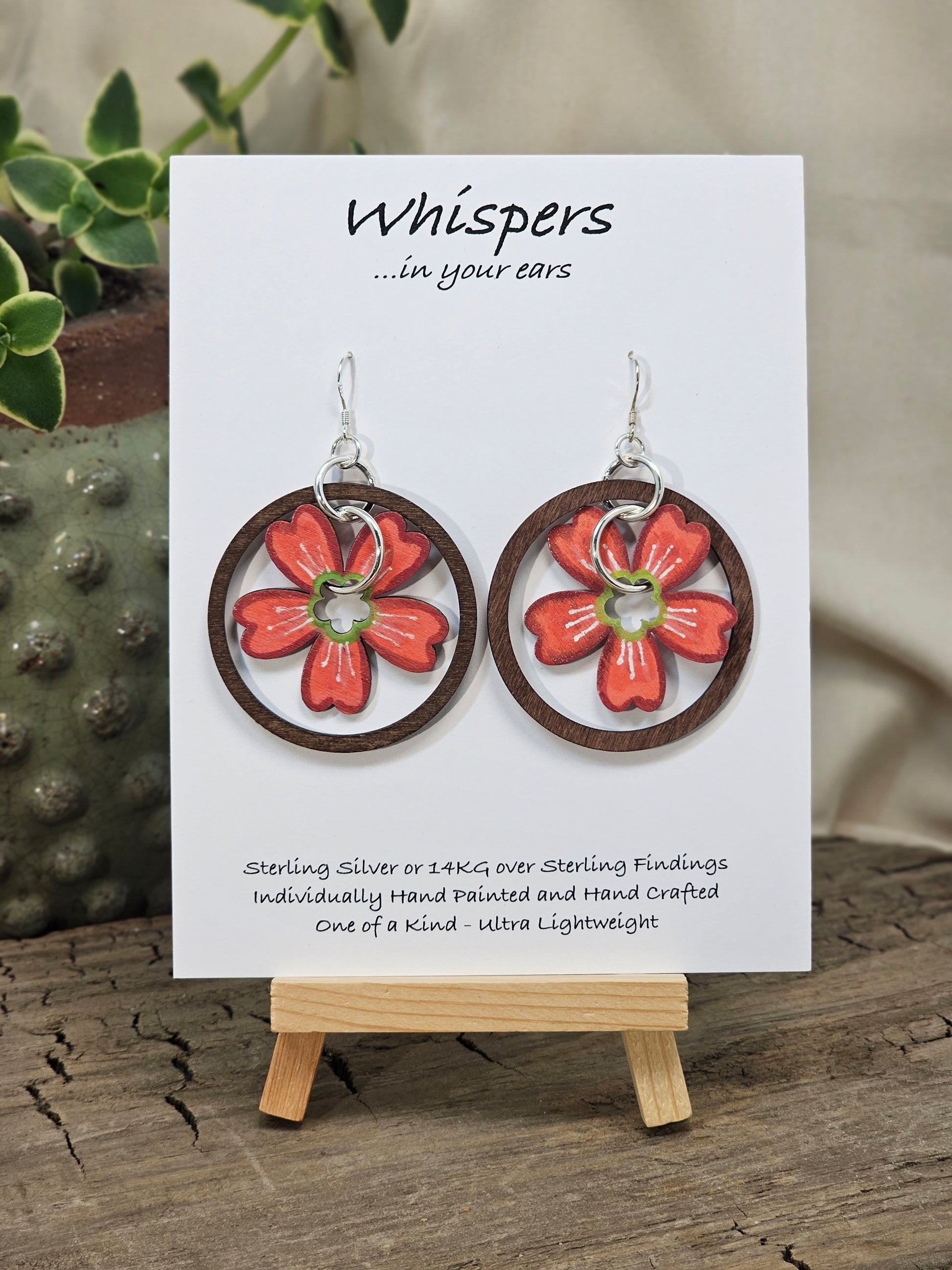 Hawaiian Plumeria Hand Painted/Crafted Earrings. These gorgeous one of a kind Statement earrings are hand painted wooden flower die cut in coral. green and white and have the same design on both sides. Sterling Silver Ear wires and large findings. Large dark stained wood circle encompasses the piece. Enameled for durability. Hangs 2" Ultra light weight