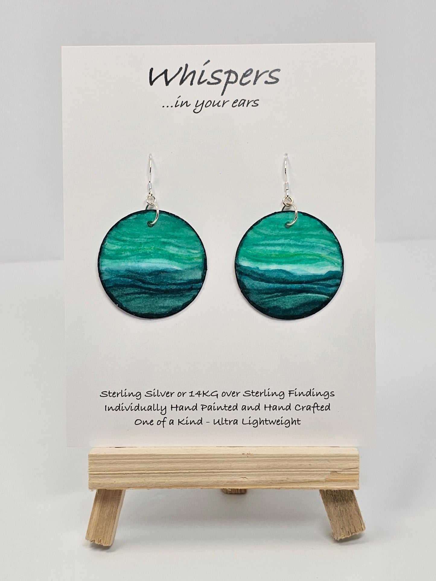 Aqua Blue and teal hand painted paper earrings. Done in watercolor. Impressionistic ocean scape. Circular in shape. Back of earring is painted to match. Ultra lightweight. Resin coated for durability. 1 1/2 in diameter. Sterling findings. Hangs 1 3/4" in length
