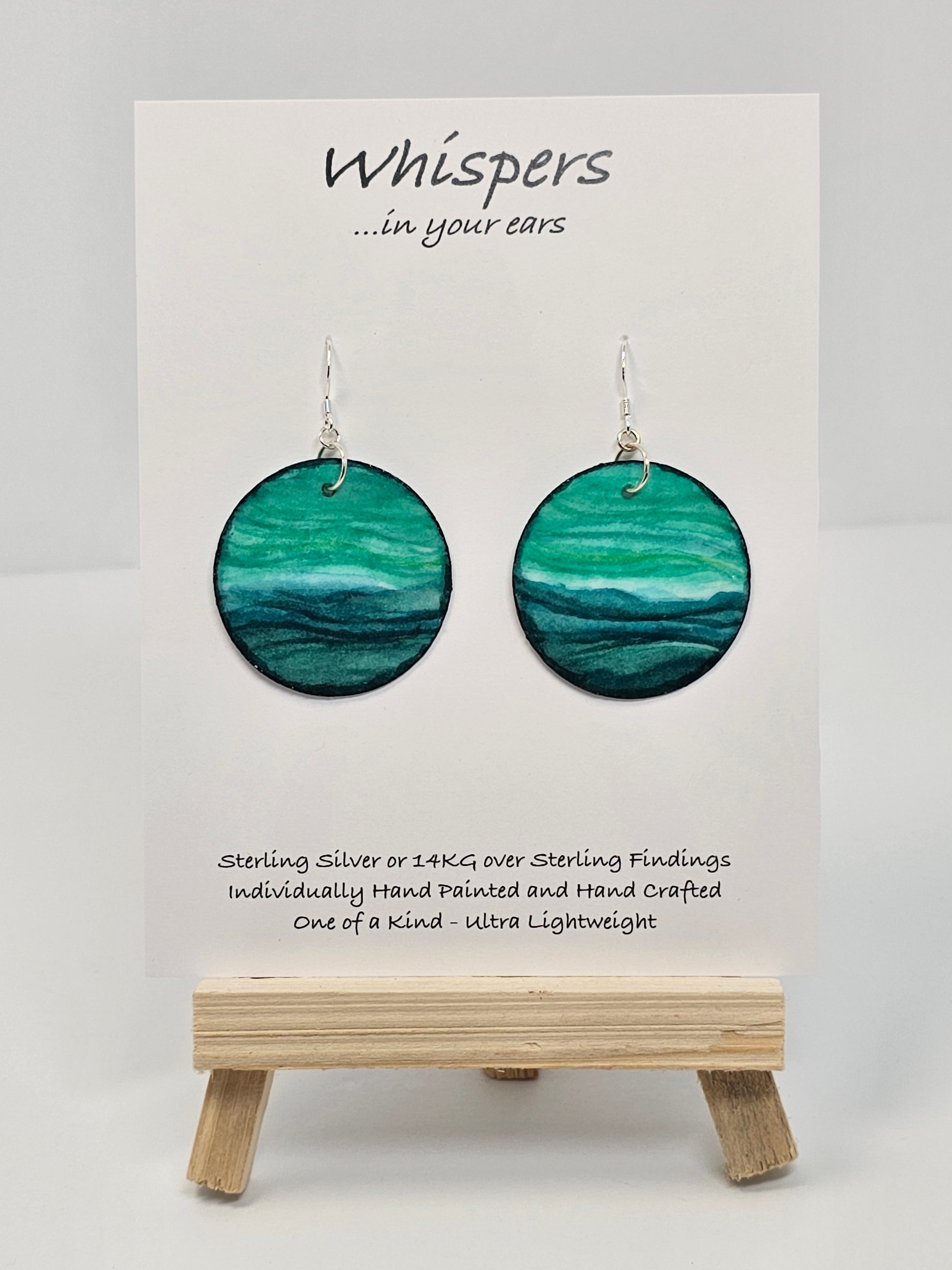 Aqua Blue and teal hand painted paper earrings. Done in watercolor. Impressionistic ocean scape. Circular in shape. Back of earring is painted to match. Ultra lightweight. Resin coated for durability. 1 1/2 in diameter. Sterling findings. Hangs 1 3/4" in length