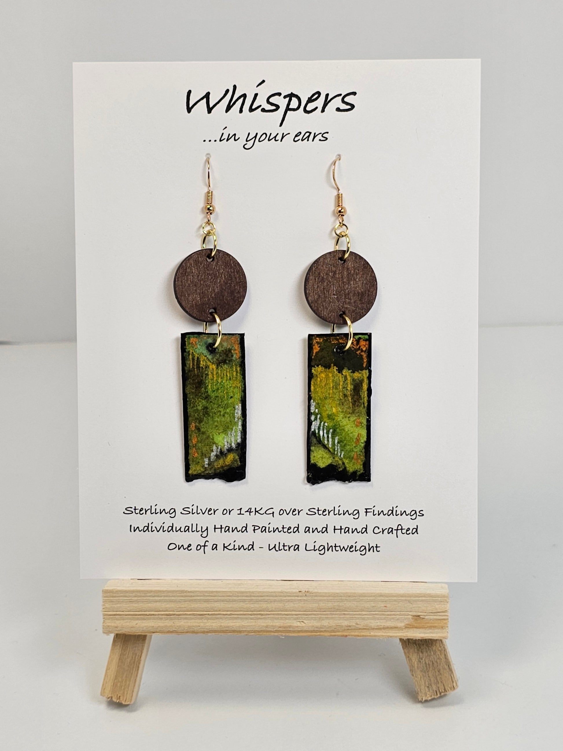 Copper, Green and Black Abstract Motif Hand Painted Paper and Wood Earrings. 1/2" x 1 5/8" Paper Rectangle hand painted brightly colored background with silver and copper accents. Edged in black. Hanging from embellished wooden disc dark brown. Back is painted to match. Resin coating for durability. Sterling Silver findings. Hangs 2 1/2" in length
