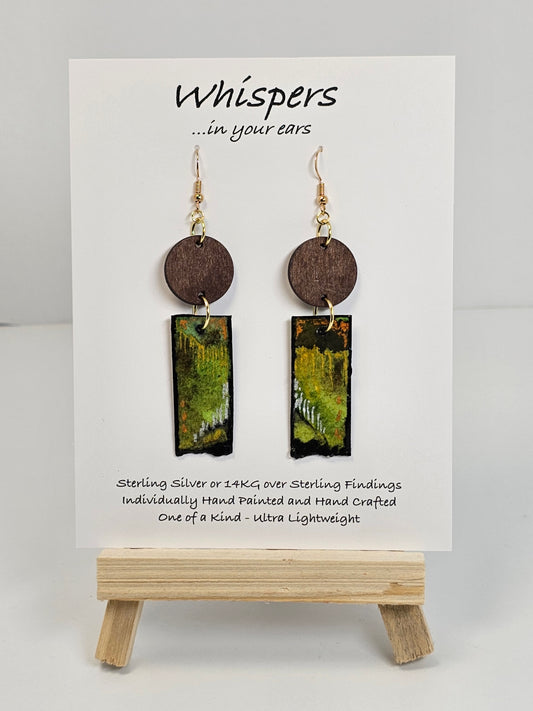 Copper, Green and Black Abstract Motif Hand Painted Paper and Wood Earrings. 1/2" x 1 5/8" Paper Rectangle hand painted brightly colored background with silver and copper accents. Edged in black. Hanging from embellished wooden disc dark brown. Back is painted to match. Resin coating for durability. Sterling Silver findings. Hangs 2 1/2" in length