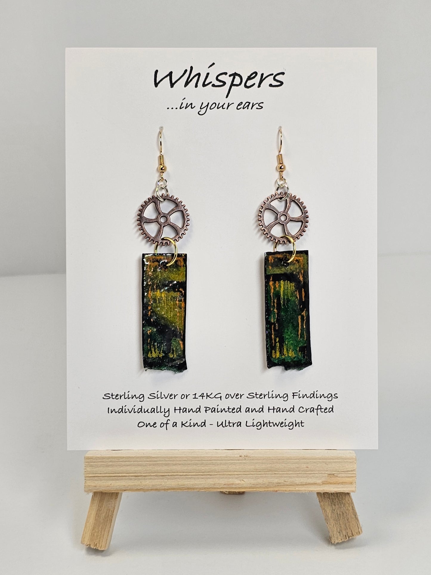 Copper Steampunk Hand Painted Paper and Wood Earrings. 1/2" x 1 5/8" Paper Rectangle hand painted brightly colored background with silver and copper accents. Edged in black. Hanging from Copper notched circular gear.  Back is painted to match. Resin coating for durability. Sterling Silver findings. Hangs 2 1/2" in length
