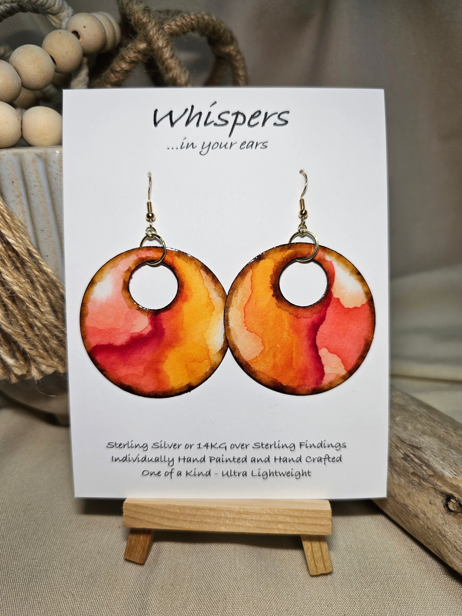 Crimson Tide Hand painted watercolor ultra lightweight paper earrings. 2" circle Waves of red, peach , pink and brown on white background. Dark brown detail painted edge. Back is painted with similar color and design. Large circular in shape with circular cut out. Resin coating for durability. 14kg over Sterling silver findings. Hangs 2 1/4" in length