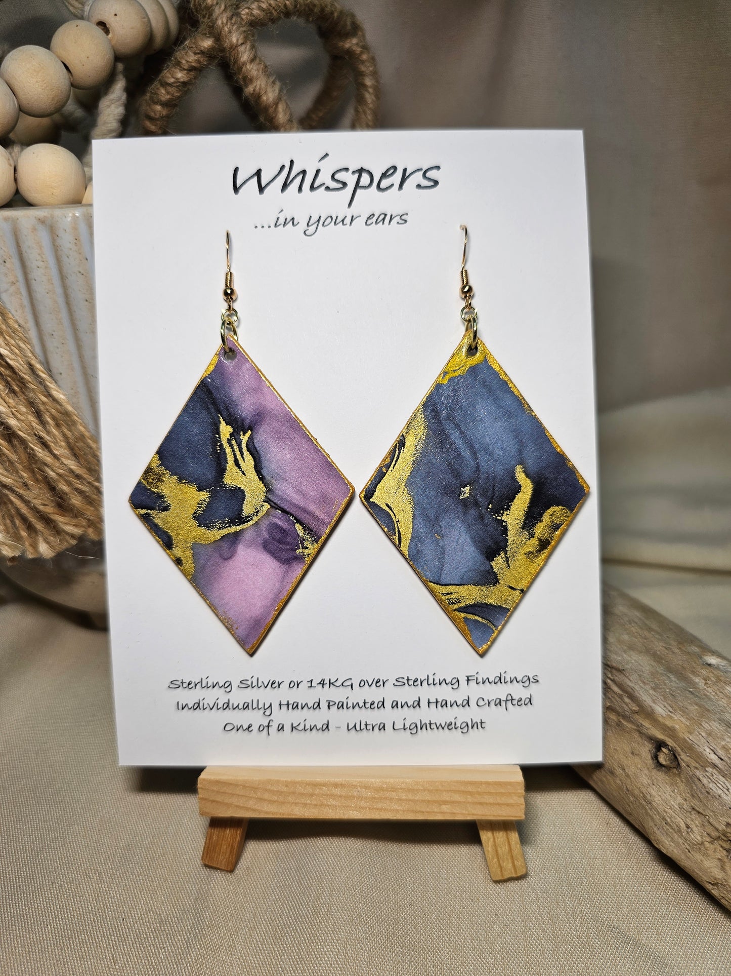 Diamond Flow Large Statement Hand Painted and collage embellished Diamond Shape Wood Earrings. Organic shapes and metallic lines,. Blues, purples and gold. Painted gold metallic edges. Back is in similar color and design. Ultra light weight. Enameled for durability. 2 3/4" in size. 14kg over sterling silver findings and hangs 3" in length