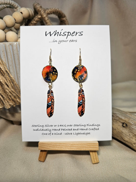 Gold Dot Feathers Hand Painted Paper Earrings. 3/4" circular hand painted paper earring. Below hangs a gorgeous light weight metal enameled feather charm pendant. Back is gold in color. Reds, blues, metallic accents edged in gold. Back of paper is painted in similar design and colors. Resin coated for durability. 14kg over sterling silver ear wires and findings. Hangs 2 1/2" in length