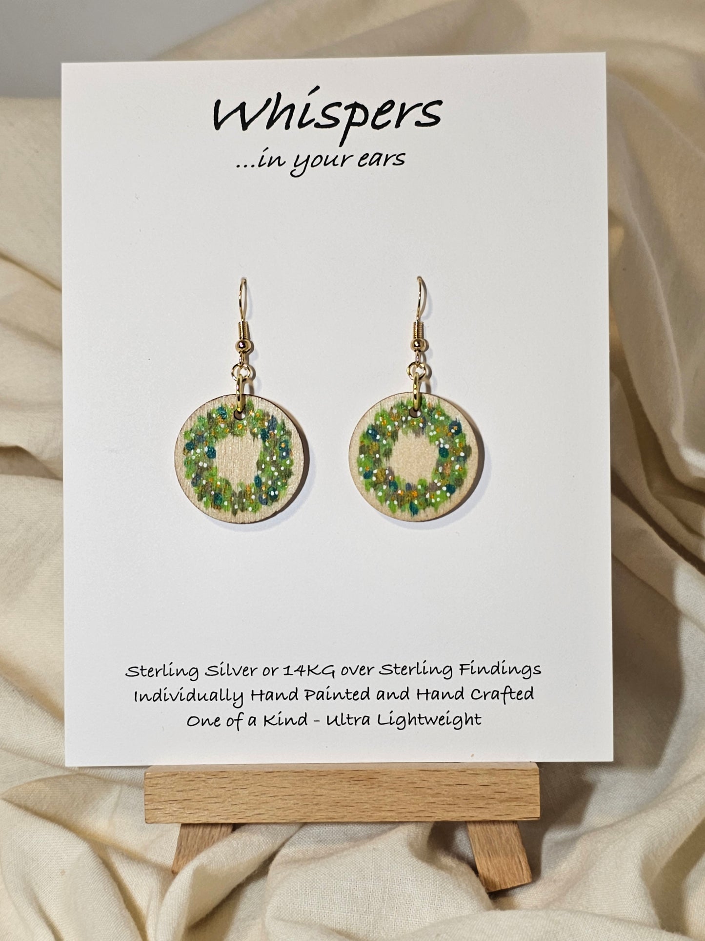 Holiday Wreath Hand Painted Wood Earrings. 1" Stained wood round, two toned Holiday wreath painted with white and colored berries. Ultra light weight. Back of earring is stained natural. Enameled for durability. 14kg over sterling ear wires and findings. Hangs 1 1/4"