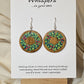 Holly Wreath Hand Painted Wood Earrings. 1 1/2" Stained wood round, two toned Holiday wreath painted with red berries. Back of earring is stained. Enameled for durability. Sterling Silver findings. Hangs 1 3/4"