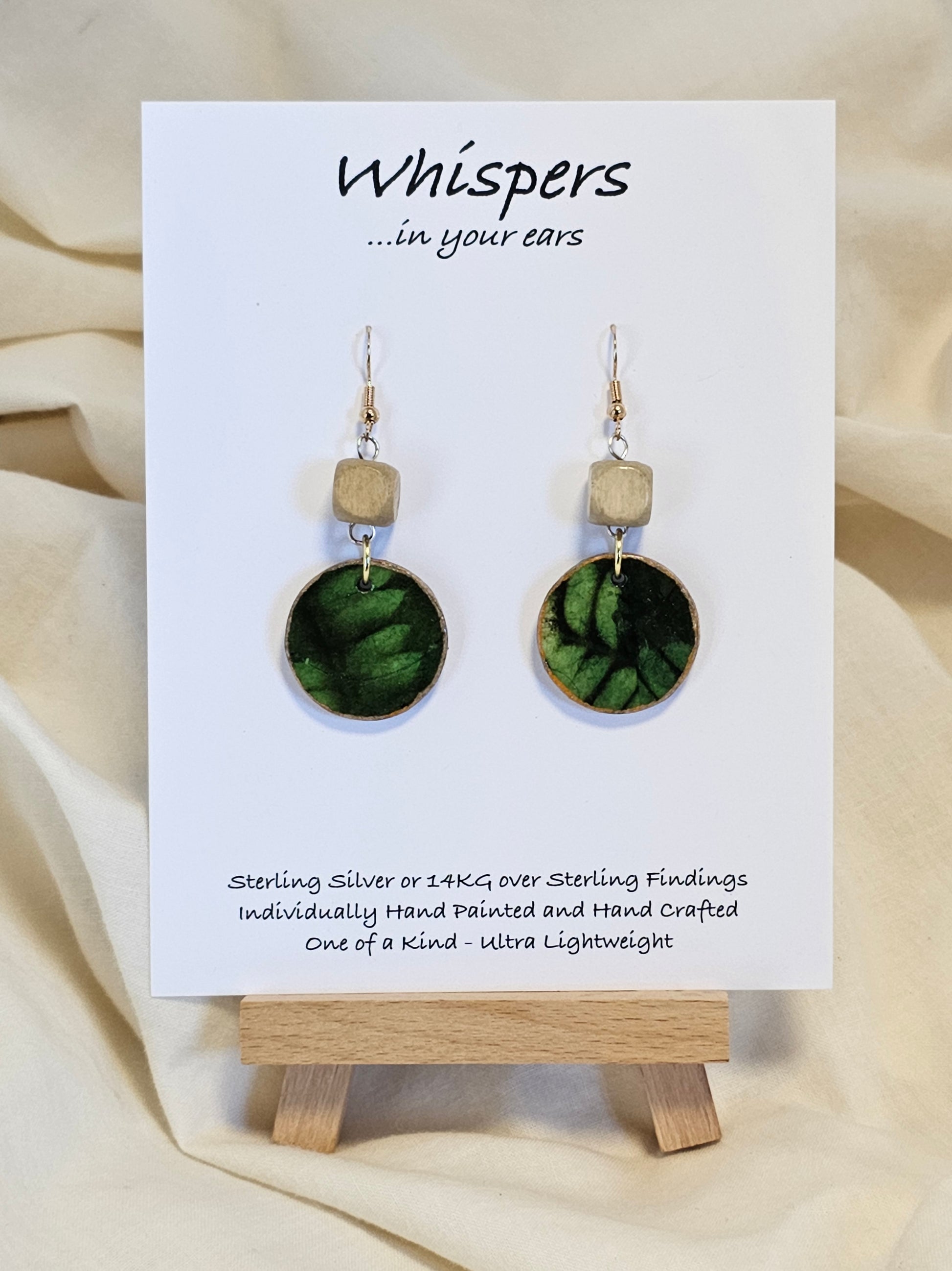 Leaf Relief Hand Crafted Wood Earrings. 1" Wood Disc with two tone green handmade paper painted gold edges and hanging from cream colored square wooden bead. Resin Coating for durability. Back is done to compliment. 14kg over sterling ear wire sterling silver findings. Hangs 1 3/4"
