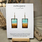 Metallic Beach Hand Painted Paper Earrings. Ultra lightweight 3/4" x 1 1/2" rectangle painted with watercolor. Depicts impressionistic beachscape. Metallic accents in sand. Edges painted in dark brown to frame the scene. Back is painted with the same design. Resin coating for durability. 14kg over sterling silver ear wires. Mixed metals. Hangs 1 3/4" in length