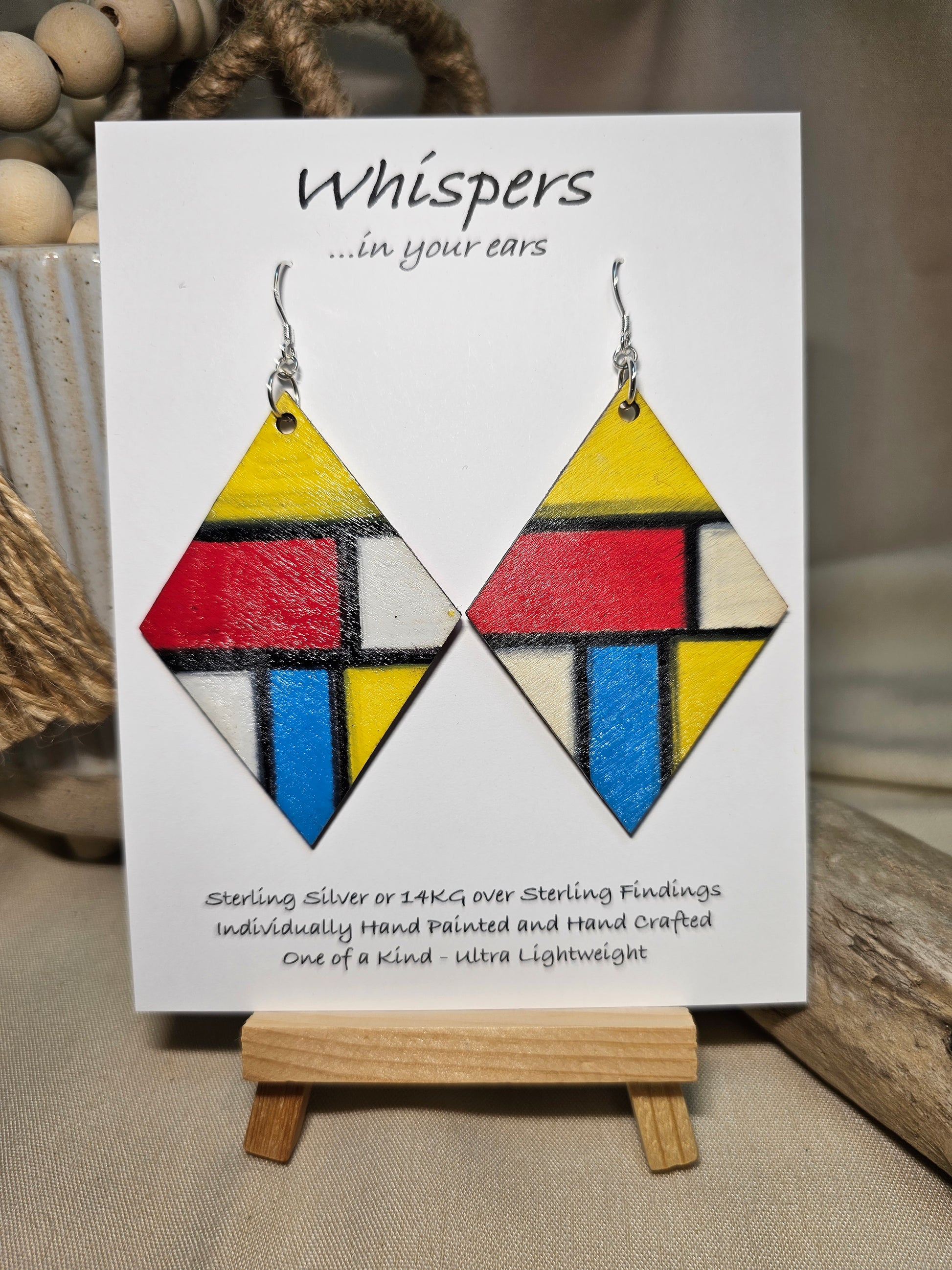 Mondrian Inspired Large Statement Hand Painted Diamond Shape Wood Earrings. Colorful rectangular shapes and black lines,. Blues red, black and white Painted black edges. Back is in similar color and design. Ultra light weight. Enameled for durability. 2 3/4" in size. Sterling silver findings and hangs 3" in length