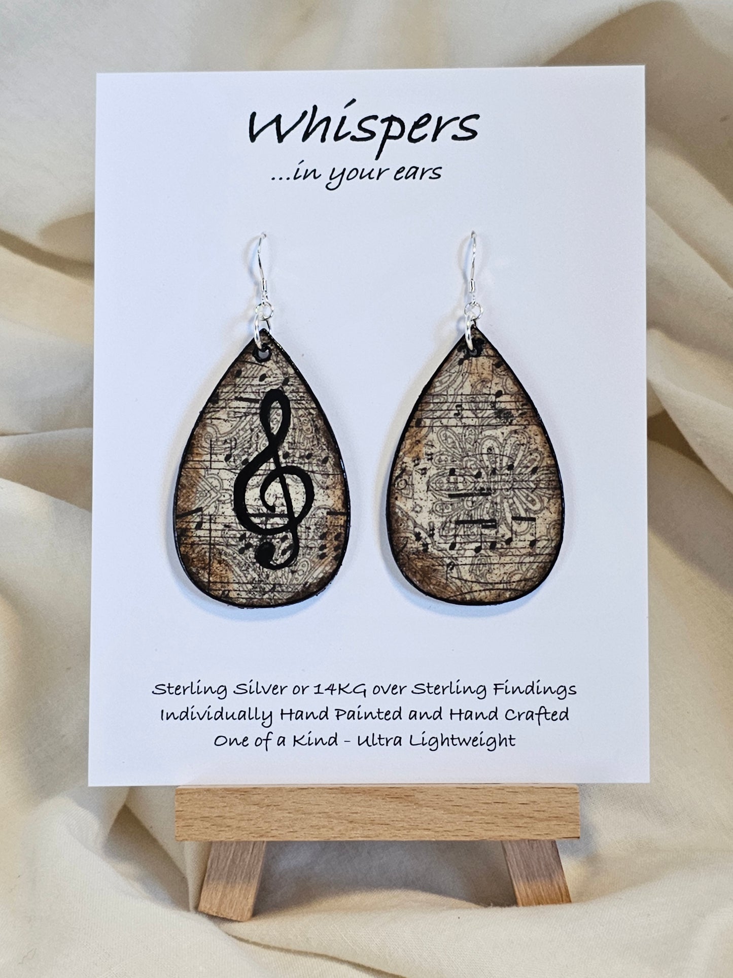 Music Notes Hand Painted/Crafted Wood Earrings. 2" Wood Tear Drop with handmade paper with painted treble cleft painted Black edges. Resin Coating for durability. Back is done to compliment. Sterling silver findings. Hangs 2 1/4"