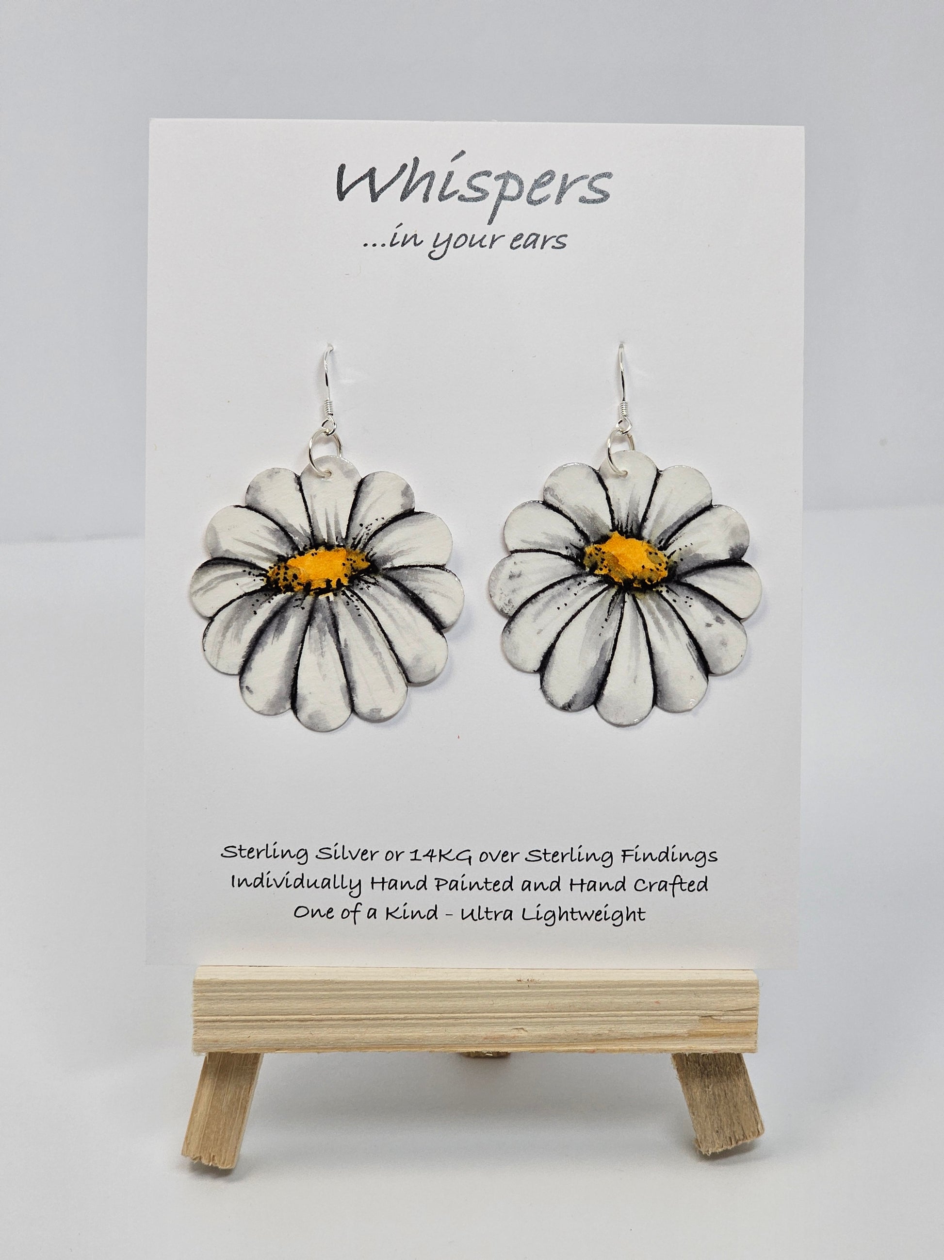 Oopsy Daisy Hand Painted Paper Earrings. Flower shaped heavy weight paper painted to resemble a white daisy with yellow center. Ultra light weight. 1 5/8" in diameter. Back of earring is painted in the same design. Resin coated for durability. Sterling silver ear wires and findings. Hangs 2"