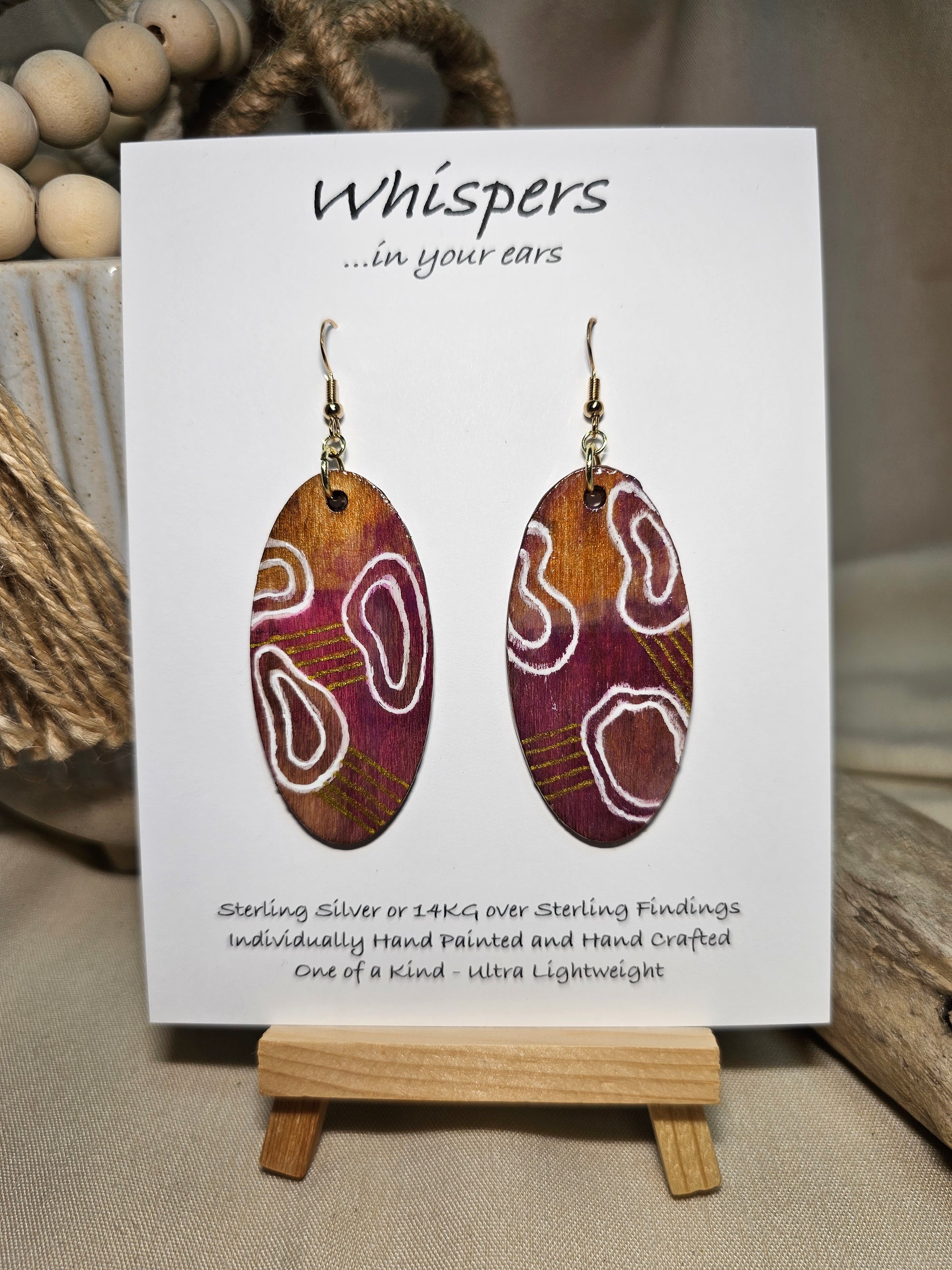 Organic Boho Hand Painted Wood Earrings. Organic shapes and metallic lines painted in acrylics. Back is painted in similar color. Ultra light weight. Resin coating for durability. 2" Elongated wood oval. 14kg over Sterling silver mixed metals with sterling silver findings and hangs 2 1/4" in length