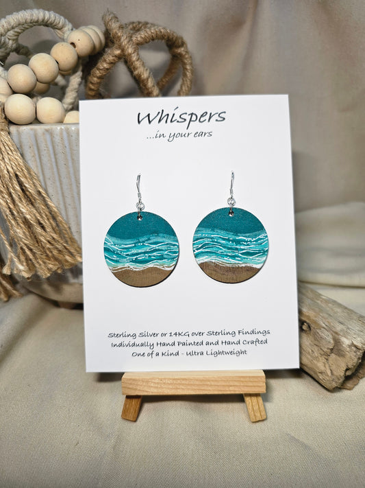 Shore Break Hand Painted Wood Earrings. 1 1/2" wooden round, Beach shoreline landscape painted with acrylics in aqua blues, teal and white. Ultra light weight. Back of earring is painted with similar design. Enameled for durability. Sterling silver ear wires and findings. Hangs 1 3/4"
