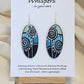 Silver Dandelion Puffball Hand Painted Wood Earrings. Geometric background in soft green, aqua blue and black. Back painted in similar design. Resin coated for durability. 2" Elongated oval wood. Sterling silver findings and hangs 2 1/4"