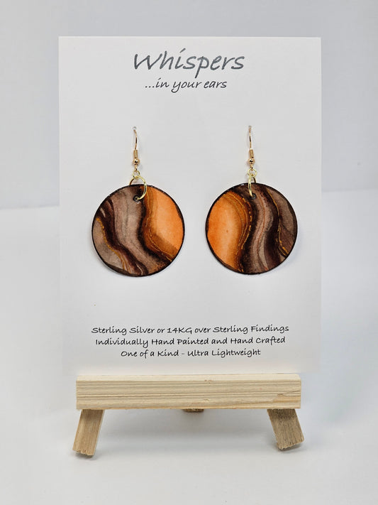 Wooden Glow Hand painted Paper earrings. Look of wood in bark pattern, orange glow and brown and dark brown lines. Gold metallic veining. Back of earring is painted to match. Ultra lightweight. Resin coated for durability. 1 1/2" diameter. 14KG over Sterling findings. Hangs 1 3/4" in length