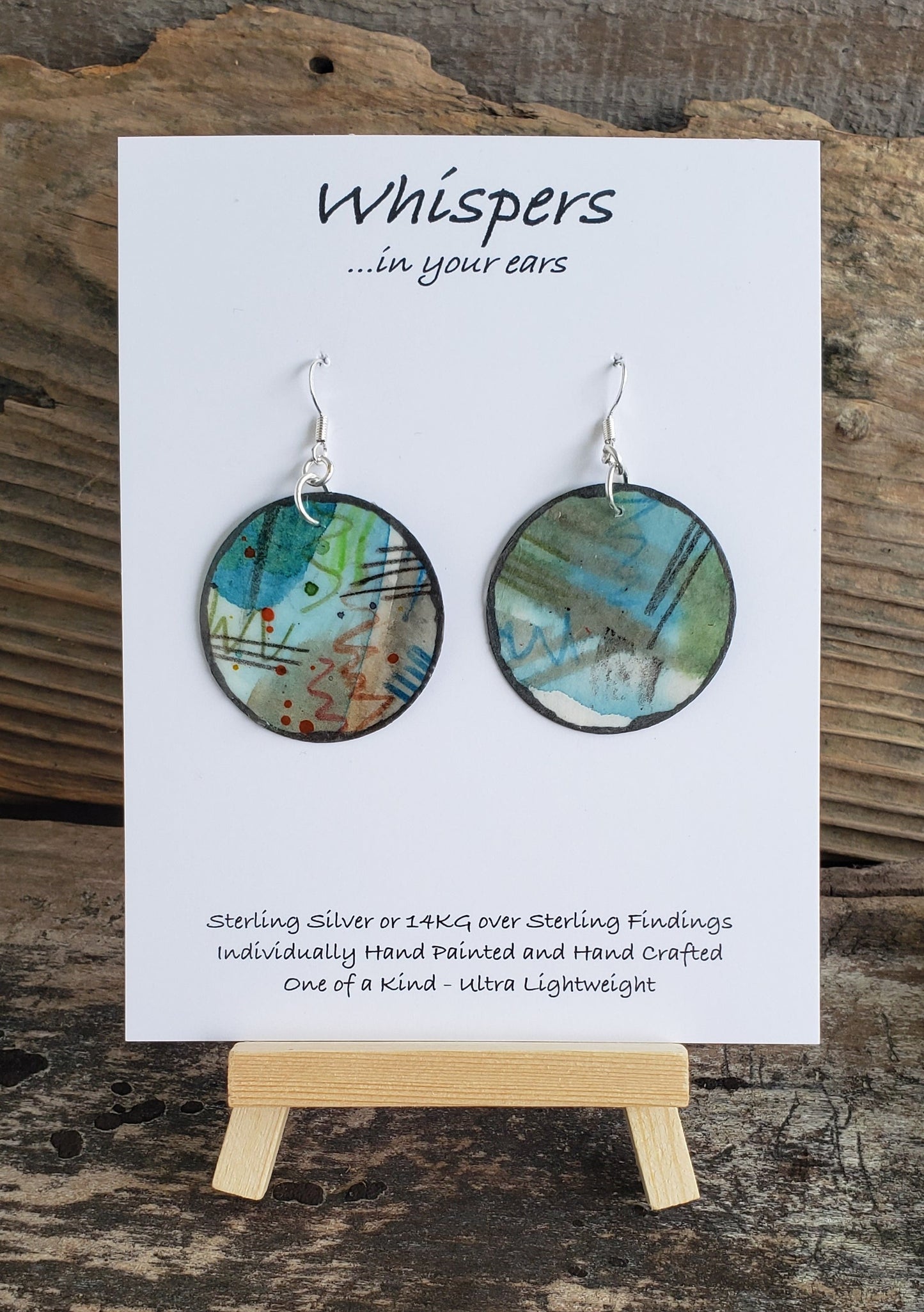 Hand painted watercolor ultra lightweight paper earrings.  Mixed media. Blues greens reds and grey abstract cosmic design.  Painted pewter edge. Back is painted similar design. Circular in shape. Sterling silver findings. Hangs 1 3/4" in Length